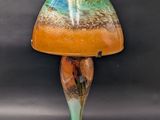 an orange and green lamp with a glass shade on a black background