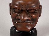 an image of a wooden sculpture of a man ' s face on a stand