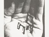 black and white photograph of a person ' s hand holding two small letters