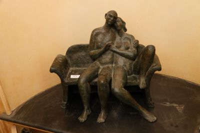 une statue en bronze représentant une femme assise sur un banc