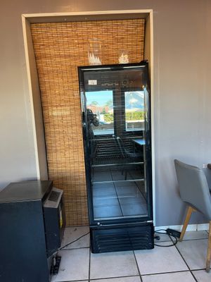 a small refrigerator in the corner of a room next to a table and chairs