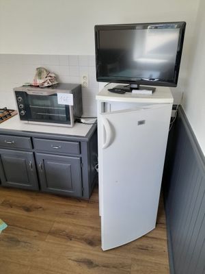 a small kitchen with a refrigerator, microwave, and a television