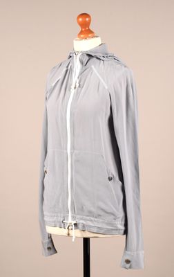veste grise posée sur un mannequin, avec une capuche blanche