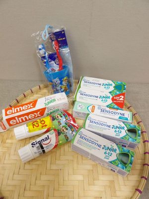 un panier sur lequel sont posés du dentifrice, des brosses à dents et encore du dentifrice