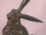 statue of a rabbit holding a piece of wood in its paws