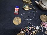 a teapot, a tea pot, a tea bag, a necklace, and a pair of scissors on a table