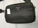 black purse with a triangle logo on it sitting on a white surface