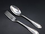 two silver spoons and a fork on a black surface