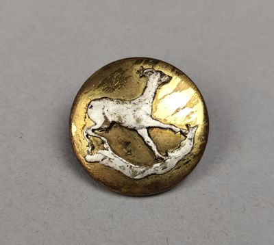 a close up of a metal button with a horse on it