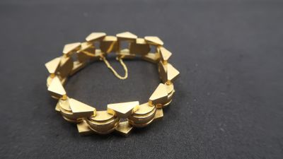 gros plan d'un bracelet en or sur une surface noire