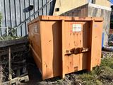 une grande benne orange garée devant un immeuble