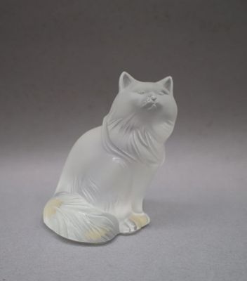 a white cat figurine sitting on a gray surface