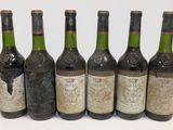 six bottles of wine are lined up in a row on a white surface