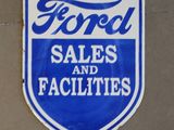 une enseigne bleue et blanche portant l'inscription « Ford Sales and Facilities » sur le côté d'un bâtiment