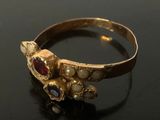 gold ring with garnetts and pearls on a black surface
