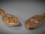 two wooden spoons with designs on them sitting on a table