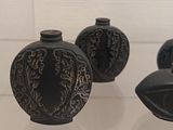 three black vases sitting on a glass table