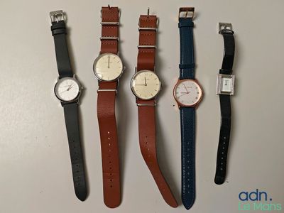 four watches are lined up in a row on a table
