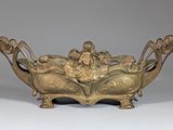 bronze bowl with figures on it on a white surface