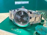 the rolex watch is sitting on a green box next to a wax seal