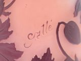 a close up of a purple vase with leaves on it