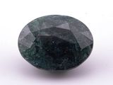 a close up of a green and black diamond on a white surface
