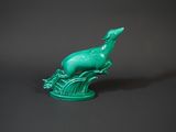 green bird figurine sitting on top of a tree branch