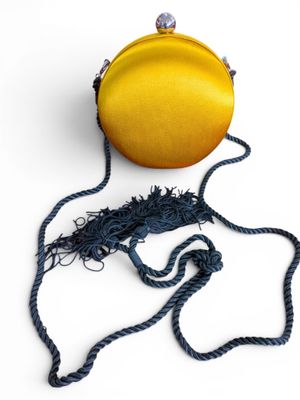 mustard colored purse with tassels on a white background