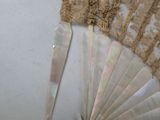 a fan with lace on it sitting on a table
