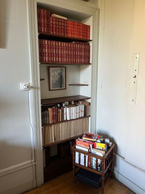 a book shelf with books on top of it in the corner of a room