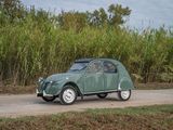 a small green car driving down a dirt road