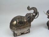 two silver elephants standing next to each other on a white surface