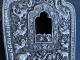 une assiette en argent finement décorée, percée d'un petit trou au milieu