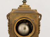 a small blue vase on top of a gold clock