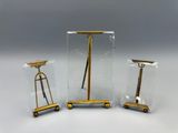 trois meubles en verre et en laiton posés sur une surface blanche