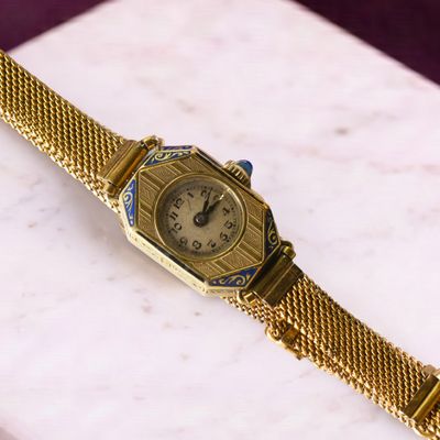 une montre en or montée sur un bracelet en or, posée sur une table en marbre