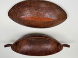 two wooden bowls with designs on them sitting next to each other