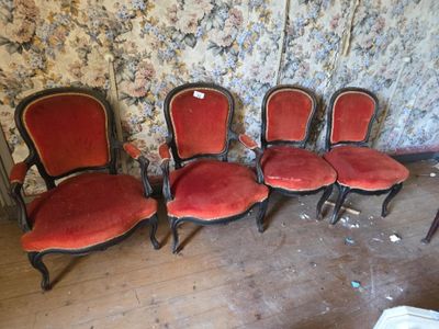quatre chaises rouges dans une pièce dont l'un des murs est recouvert de papier peint