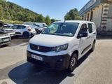 La camionnette blanche est garée sur le parking devant un immeuble.