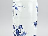 a white vase with blue flowers on it sitting on a table
