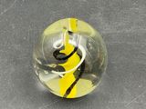 a glass ball with a yellow and black swirl inside of it