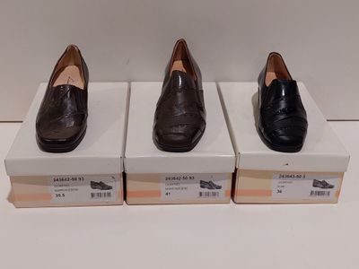 trois paires de chaussures sont posées sur des cartons, sur une surface blanche