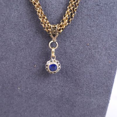 a gold chain necklace with a blue stone pendant on it