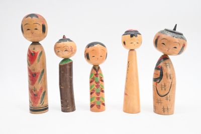 Plusieurs poupées en bois sont alignées sur une surface blanche