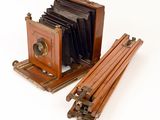 an old camera with a wooden case next to it on a white surface