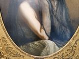 painting of a woman in a blue dress sitting in front of a gold frame