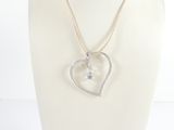 necklace with a heart shaped pendant and a diamond accent on a mannequin neck