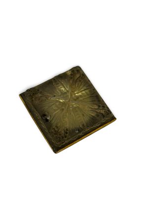 un petit objet métallique carré posé sur une surface blanche
