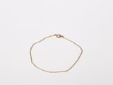 a gold chain bracelet with a small round clasp on a white background