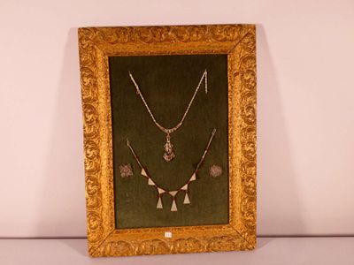 gold framed picture of a necklace and earrings on display in a gold frame